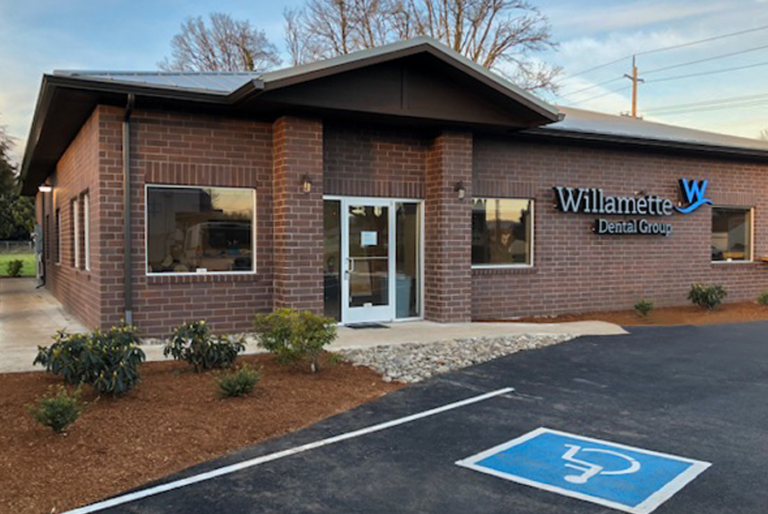 A brick dental office with large windows and decorative landscaping